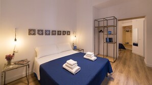 A neatly arranged hotel room with a bed, bedside tables, a wardrobe, and a mirror. - Borgo Vergini Garden (Naples)