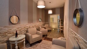 A modern lounge area with sofas, a small table with a bottle and glasses, and a mirror on the wall. - Rome Vatican Inn (Rome)