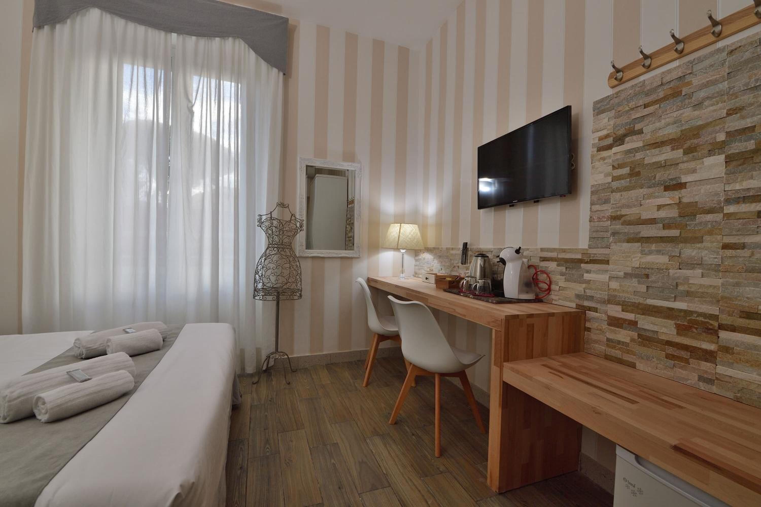 A hotel room with a bed, a desk, a chair, a TV, and a mirror.