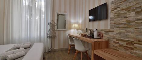 A hotel room with a bed, a desk, a chair, a TV, and a mirror.