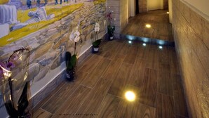 A hallway with a mural of the Colosseum, wooden flooring, and potted orchids. - Rome Vatican Inn (Rome)