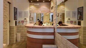A reception area with a curved reception desk, a mirror, and a seating area. - Rome Vatican Inn (Rome)