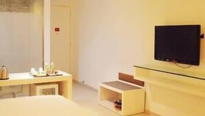 Une chambre d’hôtel moderne, équipée d’un lit, d’un téléviseur fixé au mur et d’une petite table sur laquelle sont posés divers objets.