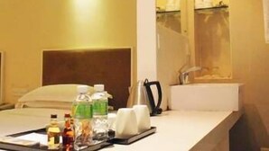 Une chambre d’hôtel comprenant un lit, une table de chevet avec des articles de toilette, un miroir et une salle de bain avec un lavabo et un miroir.