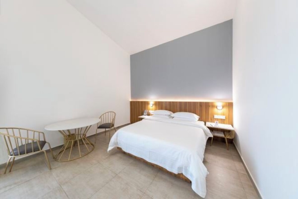 A modern hotel room with a large bed, a small round table, and a chair.