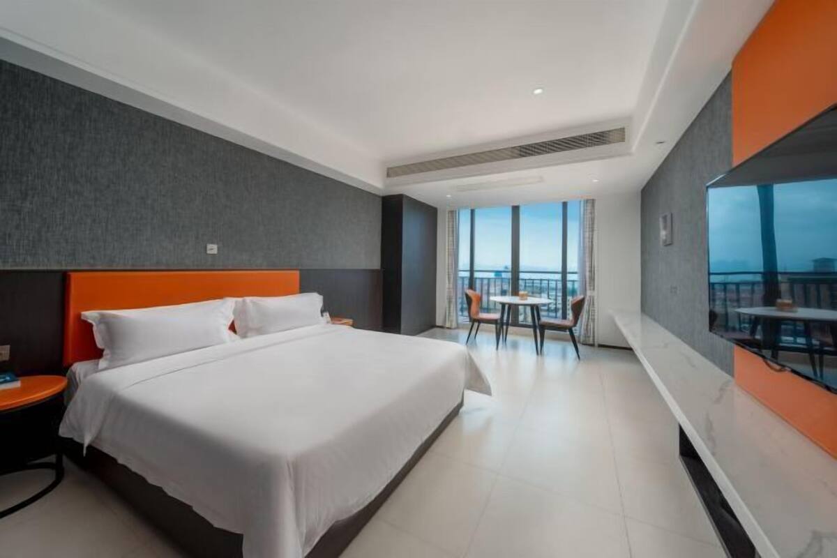 Une chambre d’hôtel avec un grand lit, un bureau, une chaise, une télévision et un balcon avec vue.