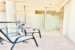 A balcony with two chairs, a small table, and a vase of flowers. - Palapart Gikas Suites And Studios (Corfu)