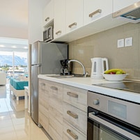 Una cocina moderna con horno empotrado, cafetera y un bol de fruta en la encimera.