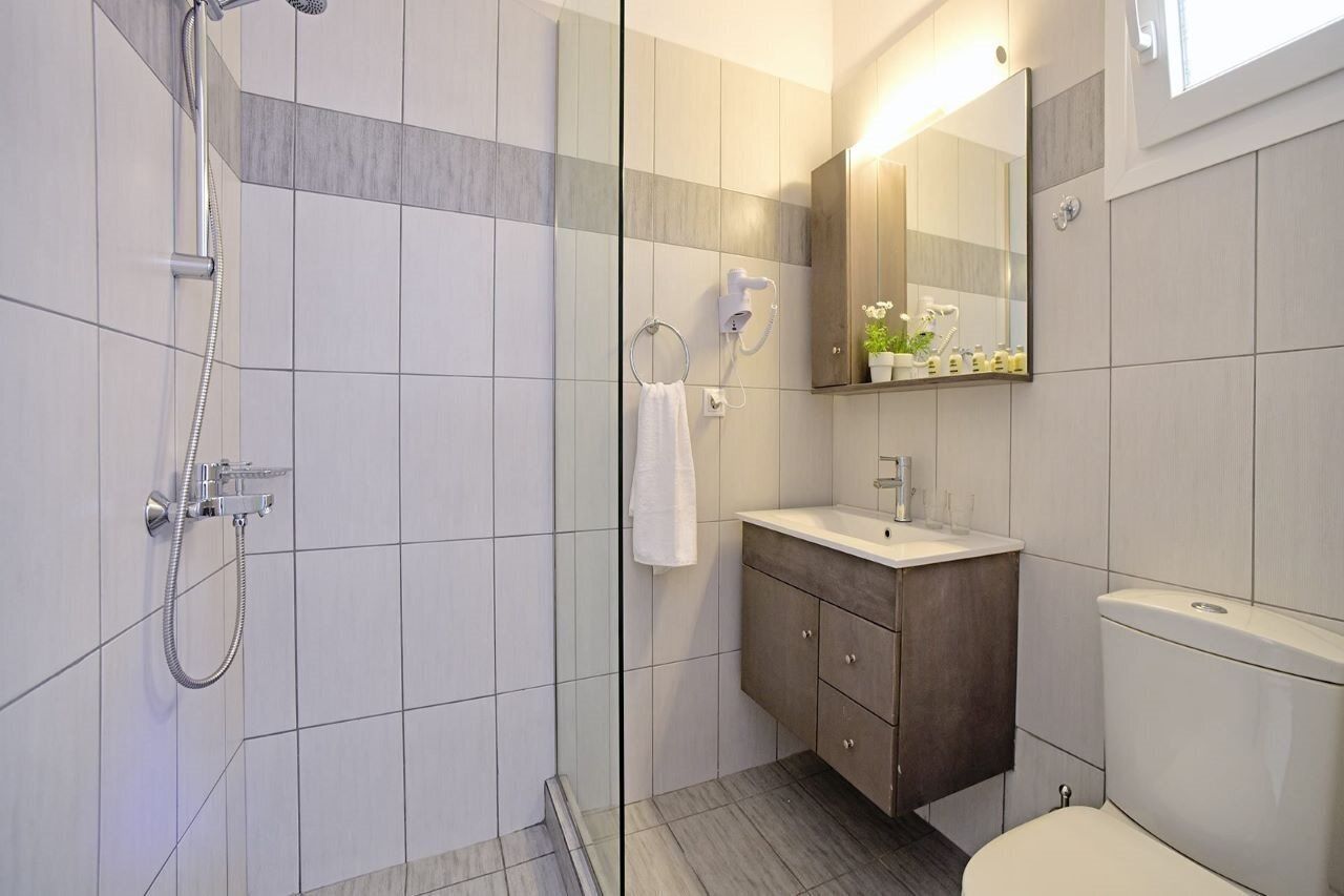 Un baño moderno con ducha de vidrio, tocador con espejo y un inodoro.