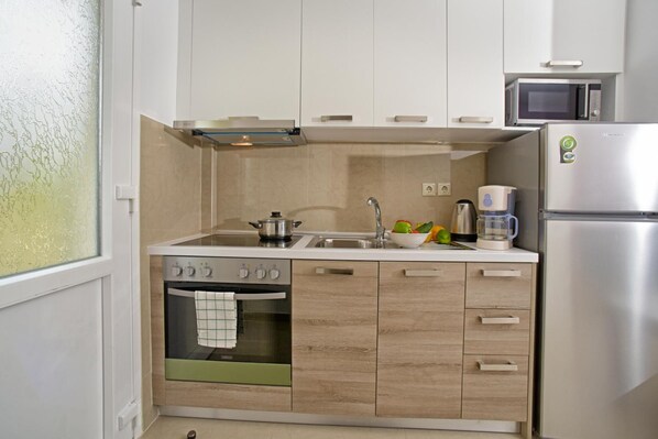 A compact kitchen with a built-in oven, a microwave, and a refrigerator.