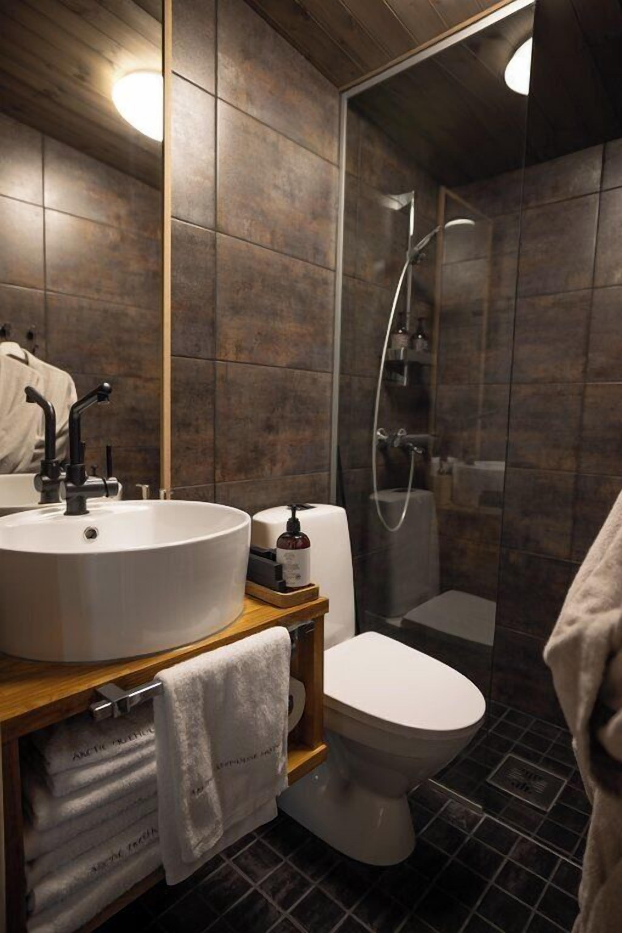 Ein modernes Badezimmer mit einem großen Waschbecken, Toilette und einer Duschkabine aus Glas.