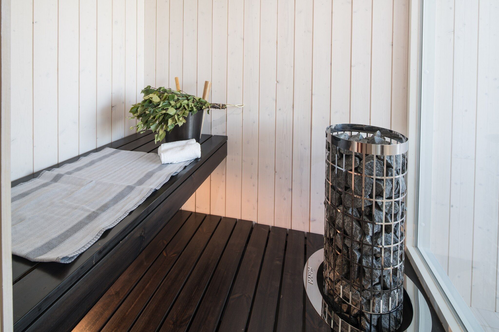 Een sauna met een houten bankje, een potplant en een stenen sauna.