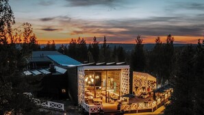 A modern building with a glass facade, a wooden deck, and a pathway leading to the entrance. - Arctic TreeHouse Hotel (Rovaniemi)