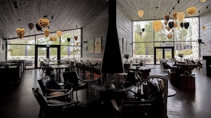 A spacious restaurant with high ceilings, wooden beams, and large windows offering views of the outdoors. - Arctic TreeHouse Hotel (Rovaniemi)