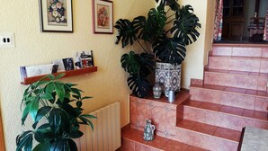 En trappe med flisegulv, en radiator og en hylde med bøger og en plante.