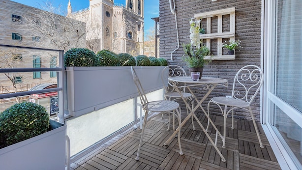 A balcony with a wooden floor, white metal chairs, a small table, and a potted plant. - Genteel Home Retiro II (Madrid)