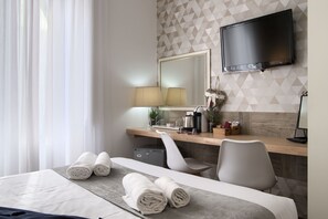 A hotel room with a bed, a desk, a chair, a TV, and a mirror. - Domus Pietro Inn (Rome)