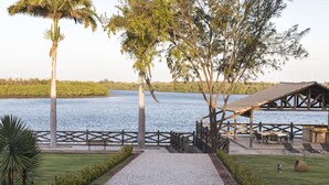 A riverside walkway with a wooden deck, seating area, and a view of the water.
