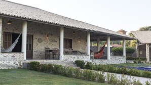 A brick house with a covered porch, outdoor seating, and a hammock.