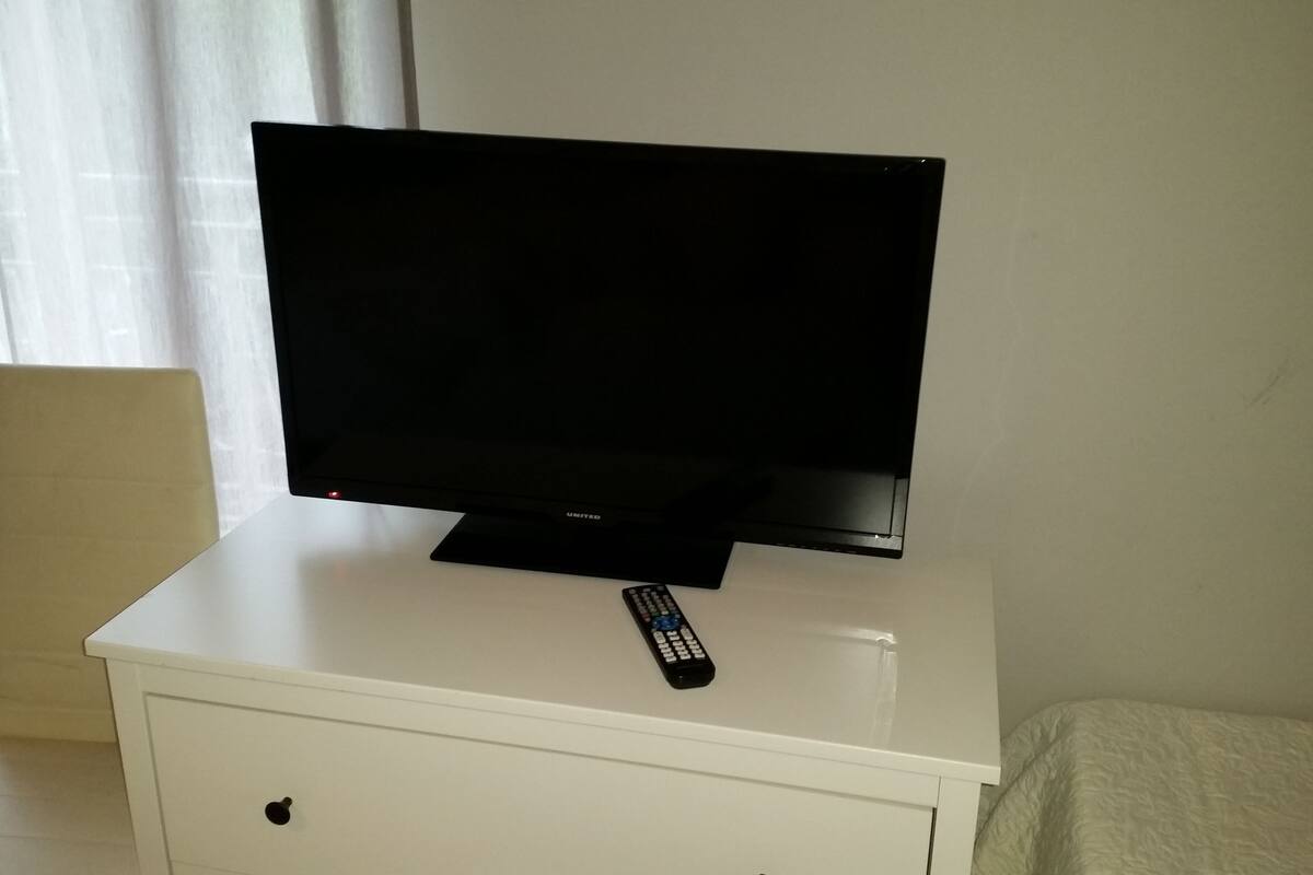 A television on a white cabinet with a remote control beside it.