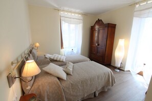 Un dormitorio con dos camas, un armario de madera y una mesita de noche con lámpara.