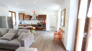A modern living room with a sofa and chairs, a kitchen with wooden cabinets and a dining area with a table and chairs. - Pitel House The Bellagio Dream (Bellagio)