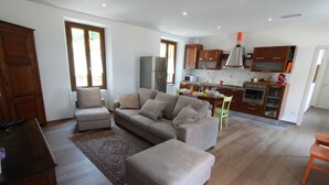 A modern living room with a sofa, ottoman, and a dining area with a table and chairs. - Pitel House The Bellagio Dream (Bellagio)