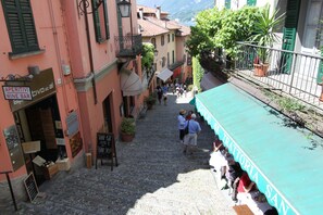 Una estrecha calle empedrada flanqueada por edificios, un letrero de bar de vinos y un restaurante con terraza.