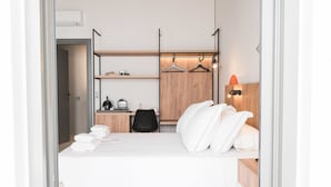 Une chambre d’hôtel moderne équipée d’un lit, d’un bureau, d’une chaise, d’une armoire et d’un luminaire suspendu.