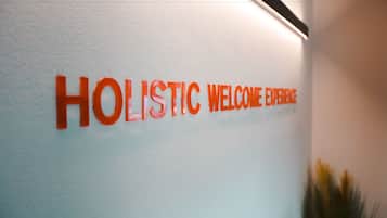 Pared con el texto "HOLISTIC WELCOME EXPERIENCE" en letras anaranjadas.
