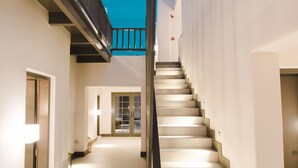 Un intérieur moderne avec un escalier menant à un niveau supérieur, caractérisé par un design minimaliste avec des murs blancs et une rampe sombre.