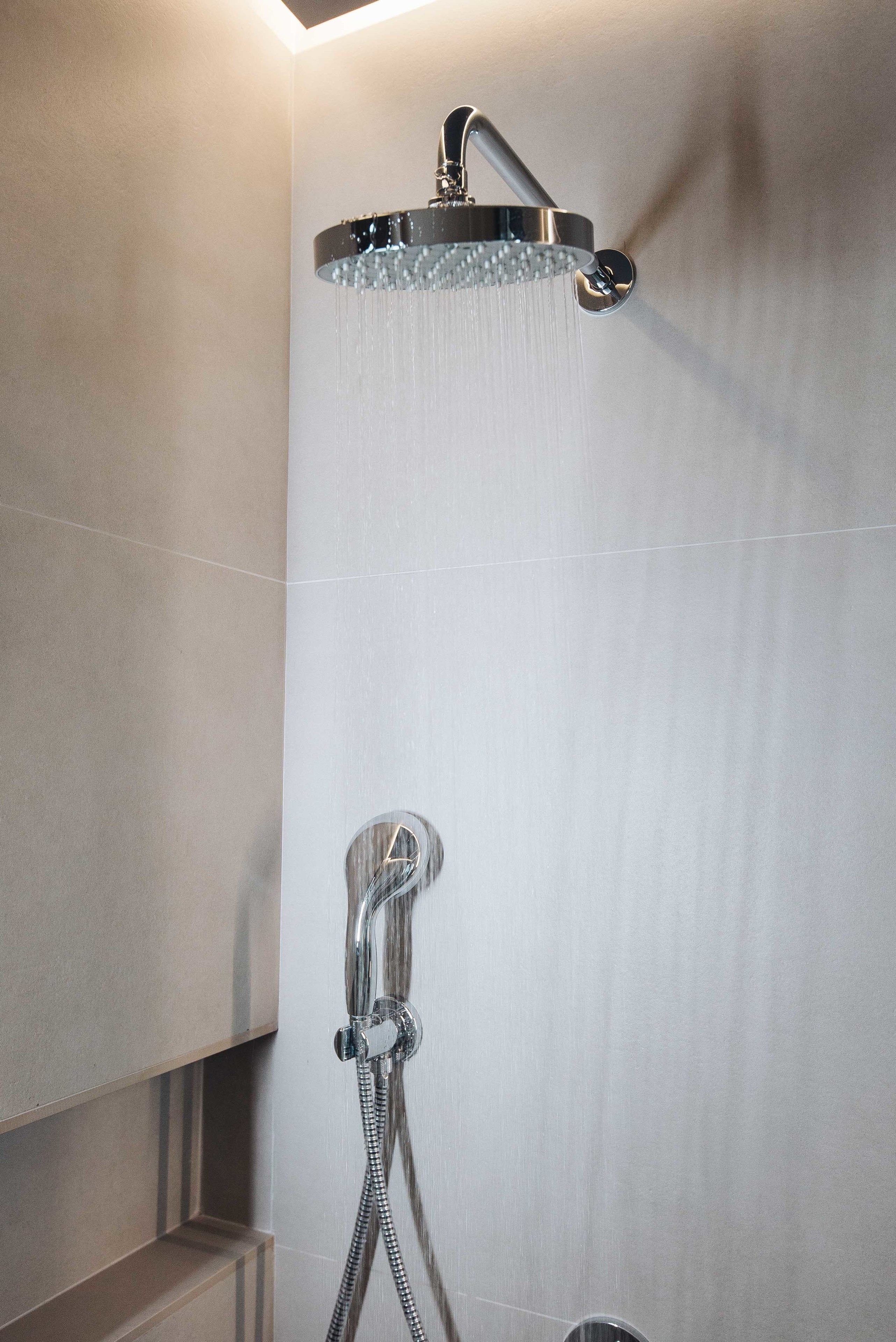 A modern shower with a rain showerhead and a handheld shower attachment.