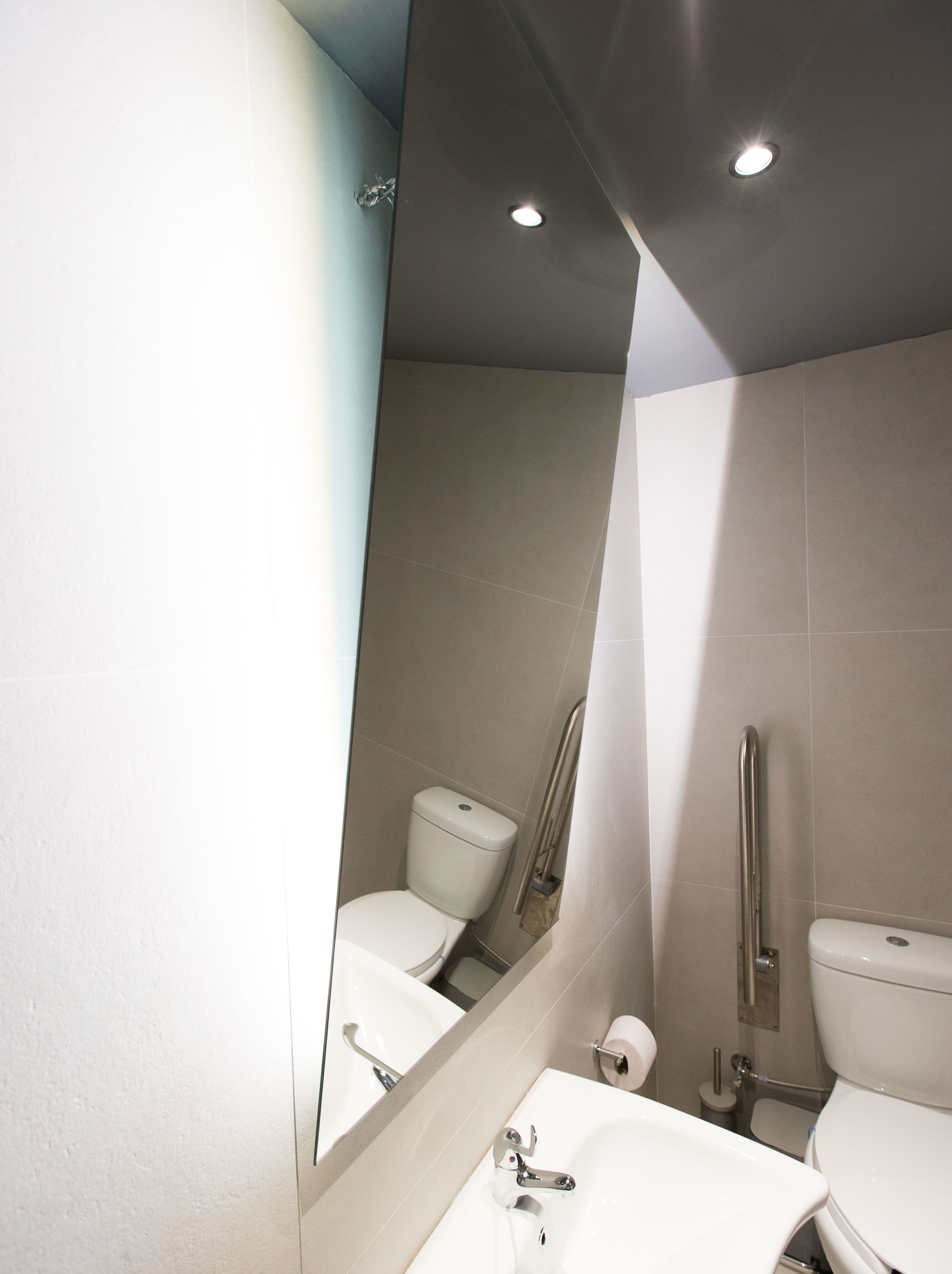 A modern bathroom with a white sink, mirror, and two toilets.