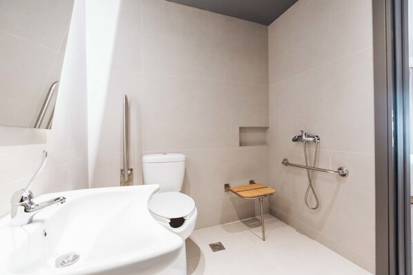 A modern bathroom with a white sink, toilet, and shower area. - Sandom (Paros)