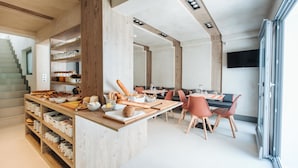Une cuisine moderne avec des poutres en bois, un coin repas avec une table et des chaises, et un escalier menant à un autre niveau.