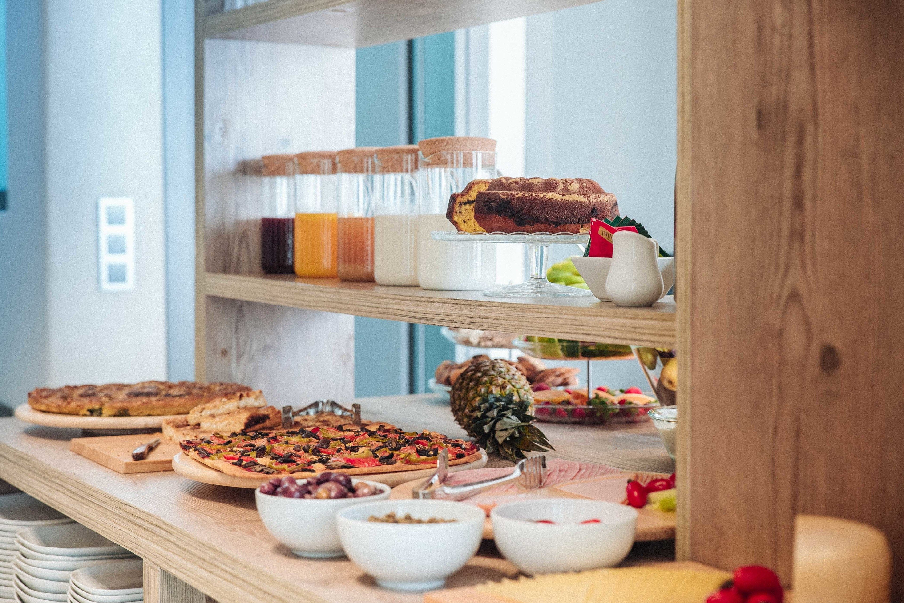 A buffet table with various food items including a pineapple, bowls of fruits, and a variety of desserts.