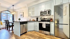 Una cocina moderna con armarios blancos, electrodomésticos de acero inoxidable y suelo de madera.