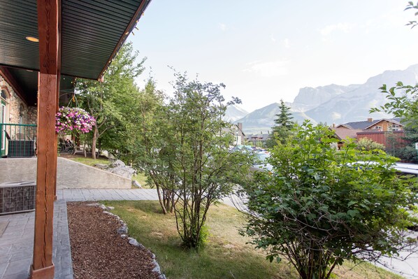 A view of a building with a stone facade, a wooden porch, and a hanging flower basket.