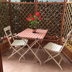 A small outdoor patio with a table and two chairs, surrounded by a wooden lattice fence. - 4Flats Orto di Venanzio (Barrea)