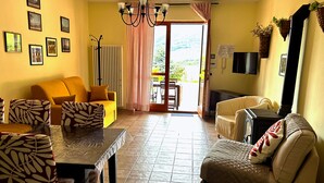 A living room with a sofa, armchairs, a dining table, and a fireplace. - 4Flats Orto di Venanzio (Barrea)