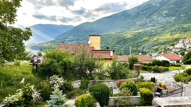 A mountainous village with traditional buildings, a paved road, and lush greenery. - 4Flats Orto di Venanzio (Barrea)