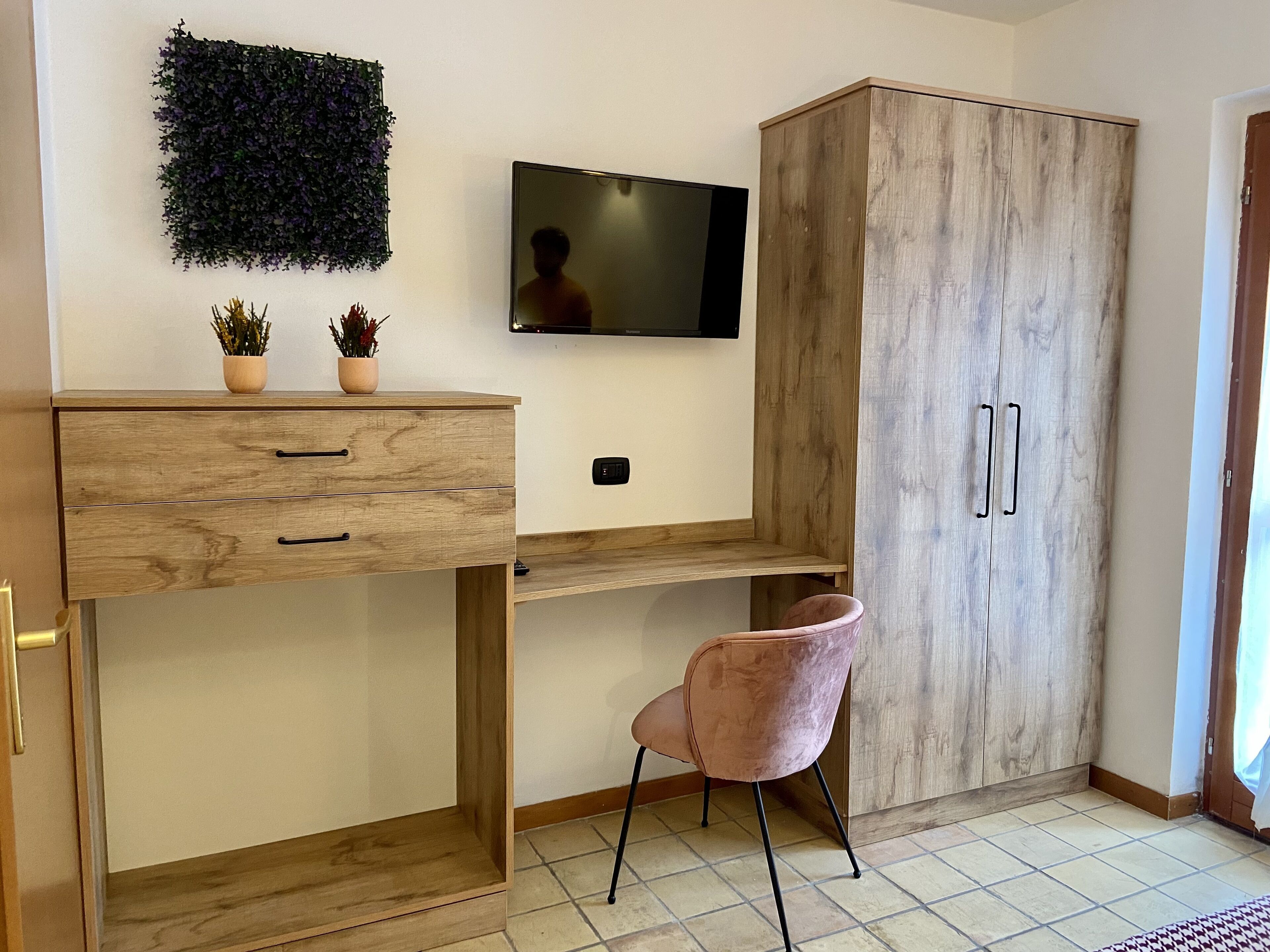 A modern room with a wooden desk, a pink chair, a TV, and a wardrobe.