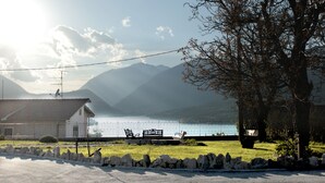 A lakeside view with a bench, a stone wall, and a building with a tiled roof. - 4Flats Orto di Venanzio (Barrea)