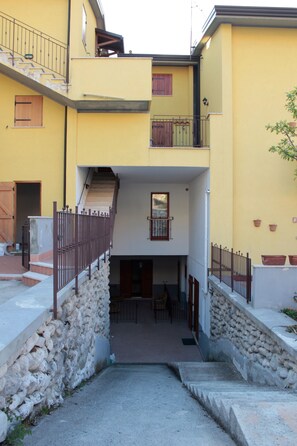 A multi-level building with a central staircase, stone walls, and a small outdoor seating area. - 4Flats Orto di Venanzio (Barrea)