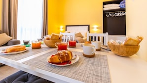 A breakfast setup with croissants, juice, and coffee on a table in a room with yellow walls and a white chair. - B&B Trianon (Naples)