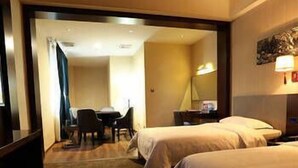 A hotel room with two beds, a desk with a chair, a nightstand, and a lamp. - Xinyiyuan Hotel (Changsha)
