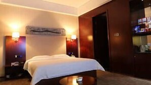 A hotel room with a bed, a small round table, a sofa, and two wall-mounted lamps. - Xinyiyuan Hotel (Changsha)
