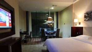 A hotel room with a large bed, a television, a desk with chairs, and a view through the window. - Xinyiyuan Hotel (Changsha)