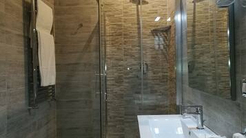 A modern bathroom with a glass-enclosed shower, a white sink, and a towel rack.