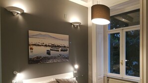 Quarto com cama, pintura de um lago e janela com vista para árvores.